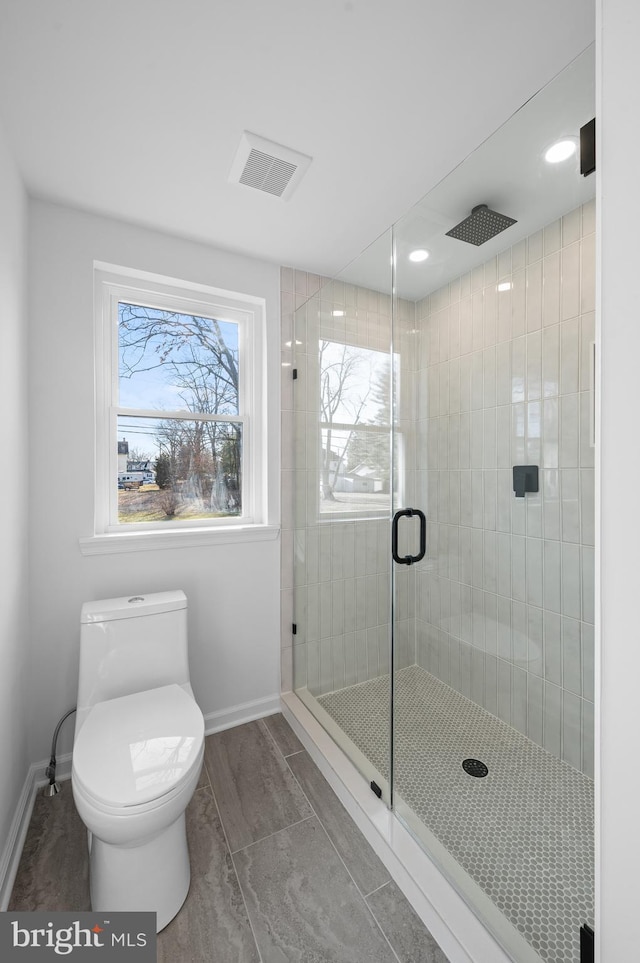 bathroom featuring toilet and a shower with shower door