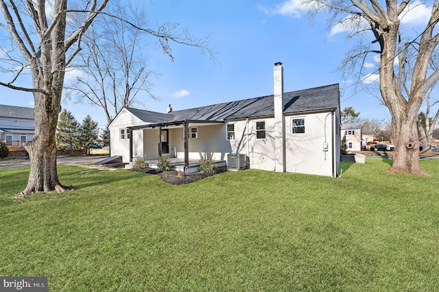 rear view of property featuring cooling unit and a lawn