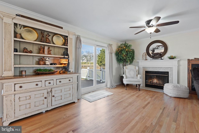 living area with ceiling fan, ornamental molding, and light hardwood / wood-style flooring