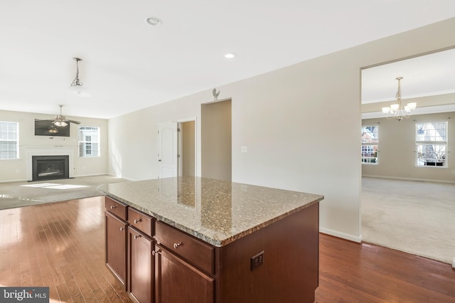 kitchen with a healthy amount of sunlight, light stone countertops, hanging light fixtures, and a kitchen island