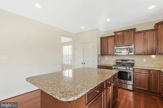 kitchen featuring appliances with stainless steel finishes, dark hardwood / wood-style flooring, a kitchen island, and backsplash