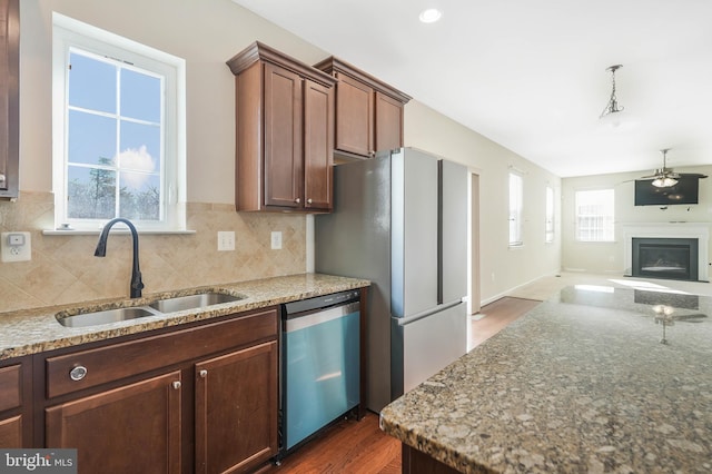 kitchen with sink, stainless steel appliances, dark hardwood / wood-style floors, light stone countertops, and decorative backsplash