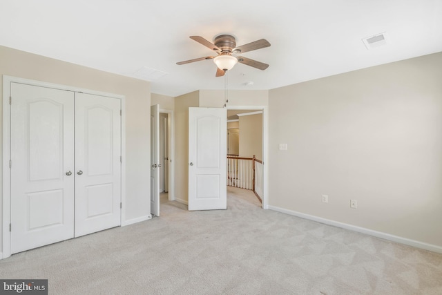 unfurnished bedroom featuring light colored carpet, ceiling fan, and a closet