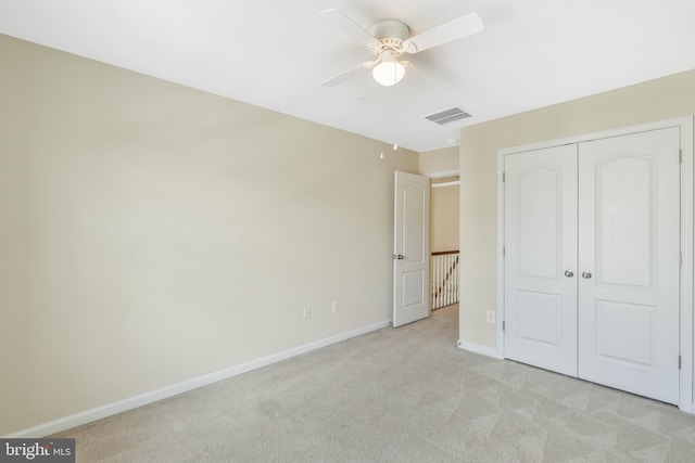 unfurnished bedroom with light colored carpet, ceiling fan, and a closet