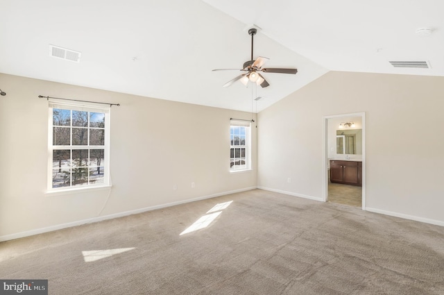 empty room featuring vaulted ceiling, light colored carpet, and ceiling fan