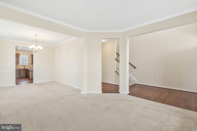 unfurnished room featuring crown molding, sink, a chandelier, and dark carpet