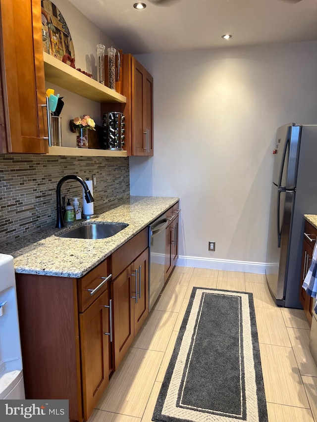 kitchen with decorative backsplash, appliances with stainless steel finishes, sink, and light stone counters