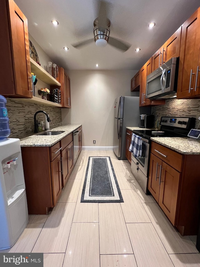 kitchen featuring light stone countertops, stainless steel appliances, decorative backsplash, and sink