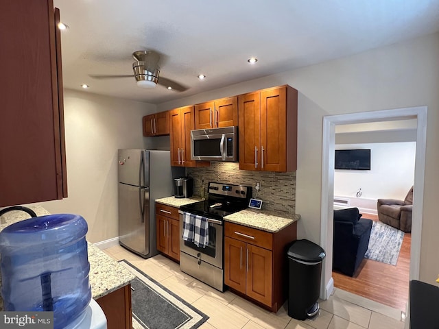 kitchen with ceiling fan, decorative backsplash, light stone countertops, stainless steel appliances, and light tile patterned floors