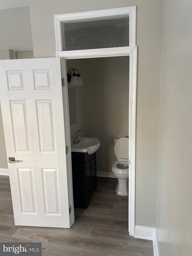 bathroom with toilet, vanity, and hardwood / wood-style floors