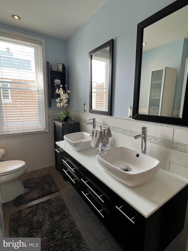 bathroom with tile walls, toilet, vanity, and tile patterned flooring