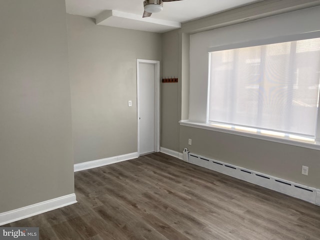 spare room featuring baseboard heating, dark hardwood / wood-style floors, and ceiling fan