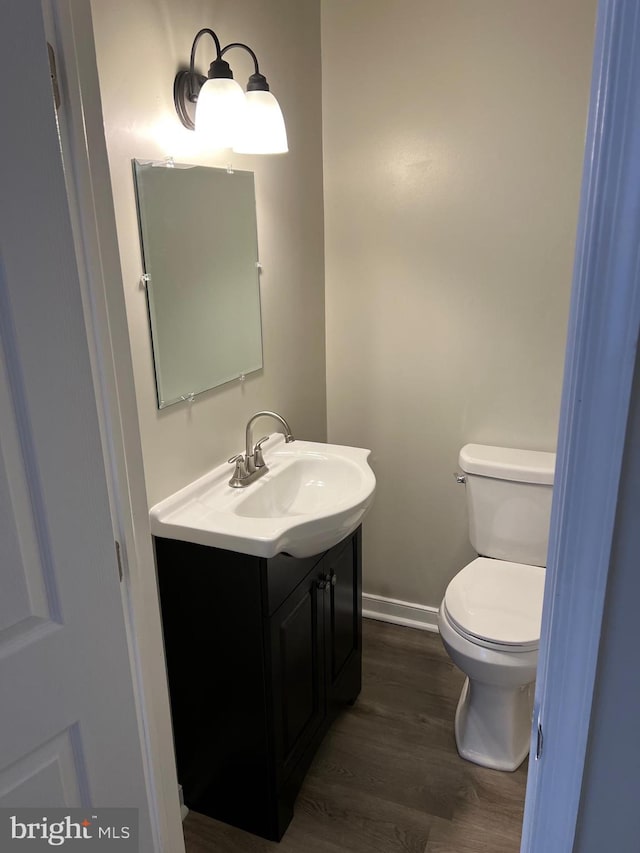 bathroom with toilet, vanity, and wood-type flooring