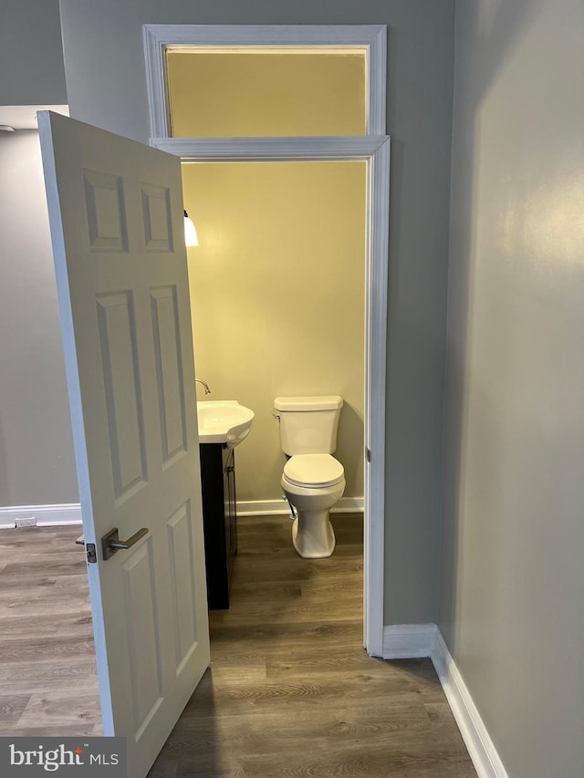 bathroom with toilet, hardwood / wood-style floors, and vanity