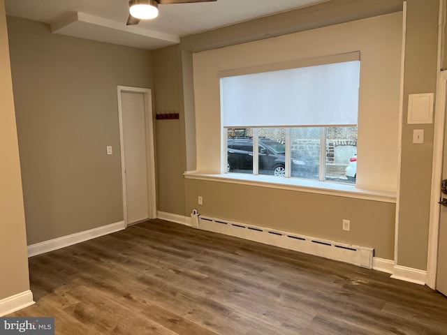 empty room with ceiling fan, baseboard heating, and dark hardwood / wood-style flooring