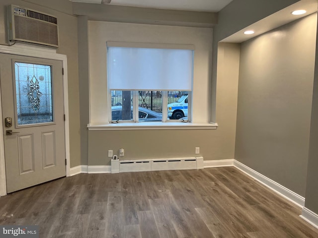 entryway featuring a wall unit AC, baseboard heating, and hardwood / wood-style floors