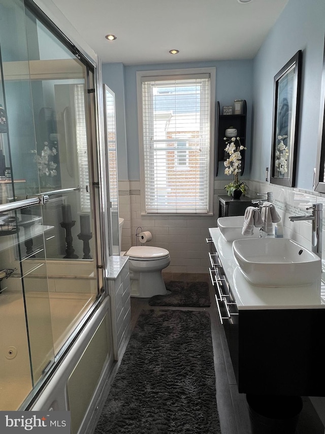 full bathroom with toilet, vanity, tile walls, tile patterned flooring, and enclosed tub / shower combo