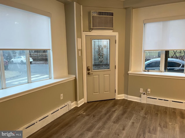 doorway to outside featuring baseboard heating, dark hardwood / wood-style flooring, and a wall unit AC