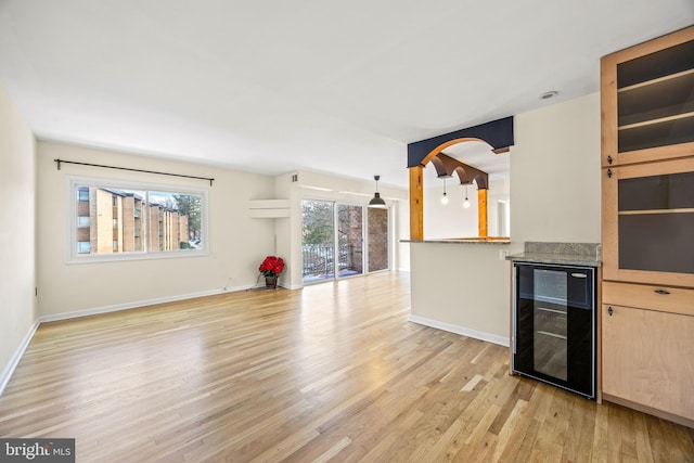 unfurnished living room with light wood-type flooring and wine cooler