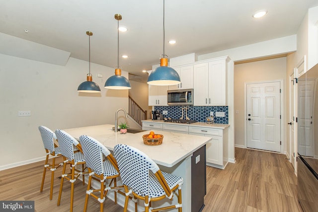 kitchen with decorative backsplash, appliances with stainless steel finishes, pendant lighting, and white cabinetry