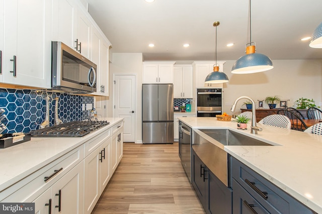 kitchen featuring stainless steel appliances, white cabinets, decorative backsplash, and pendant lighting