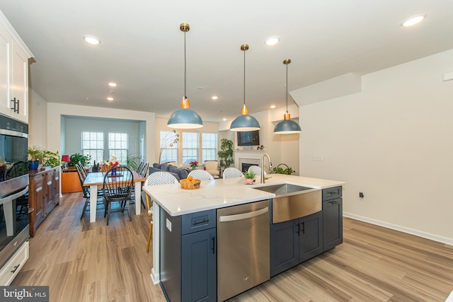 kitchen with stainless steel dishwasher, white cabinets, sink, and pendant lighting