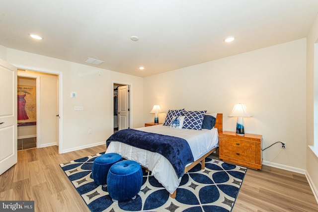 bedroom with a spacious closet, a closet, and light hardwood / wood-style flooring