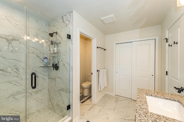 bathroom with a shower with door, vanity, and toilet