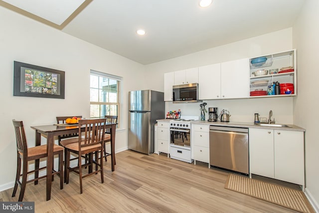 kitchen with sink, stainless steel appliances, white cabinetry, and light wood-type flooring