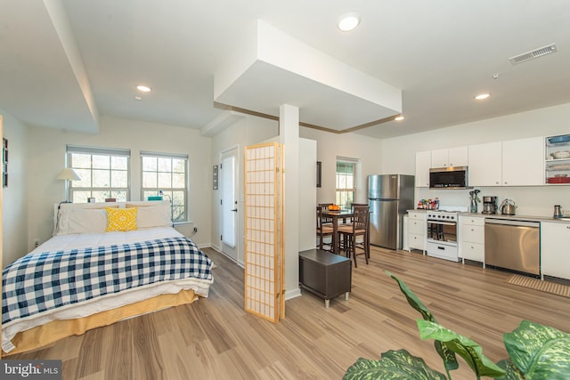 bedroom featuring stainless steel refrigerator and light wood-type flooring