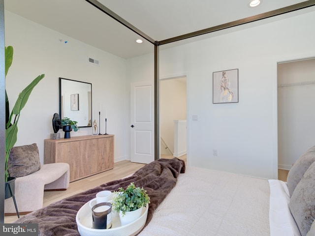 bedroom with a walk in closet, a closet, and hardwood / wood-style floors