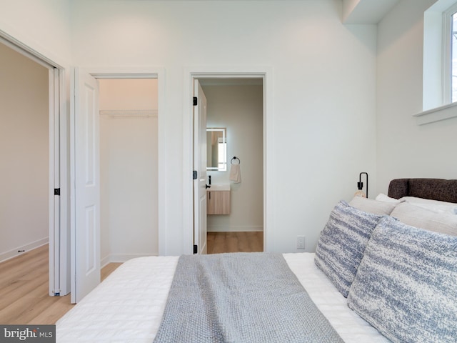 bedroom with light hardwood / wood-style floors, a walk in closet, multiple windows, and a closet