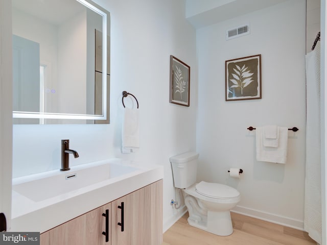 bathroom with wood-type flooring, vanity, and toilet