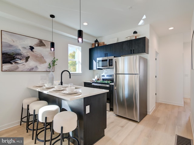 kitchen with kitchen peninsula, appliances with stainless steel finishes, a breakfast bar, sink, and hanging light fixtures