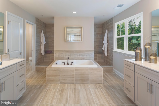 bathroom featuring tile patterned floors, vanity, toilet, and tiled tub