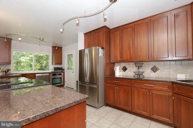 kitchen featuring dark stone counters, sink, light tile patterned floors, tasteful backsplash, and stainless steel appliances