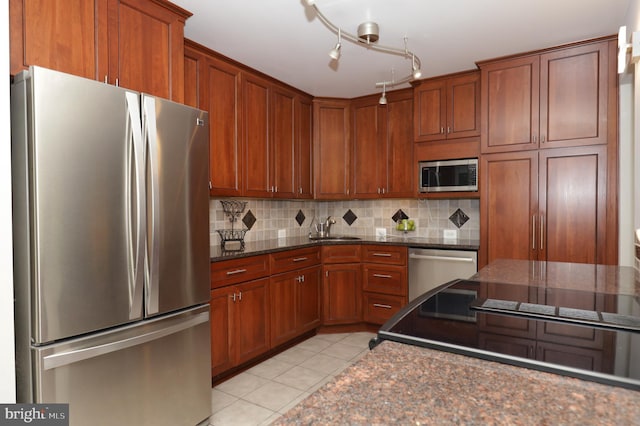 kitchen featuring backsplash, stainless steel appliances, sink, light tile patterned floors, and dark stone countertops