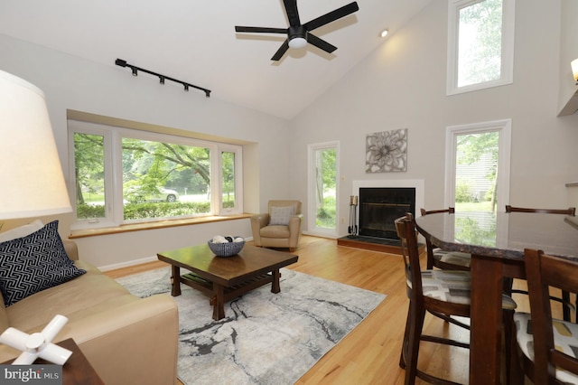 living room with ceiling fan, high vaulted ceiling, and light wood-type flooring