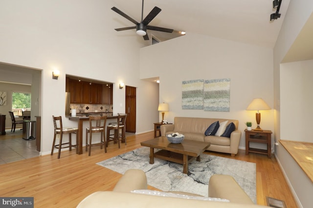 living room featuring ceiling fan, high vaulted ceiling, and light hardwood / wood-style floors