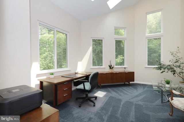 office area with carpet floors, a skylight, and high vaulted ceiling