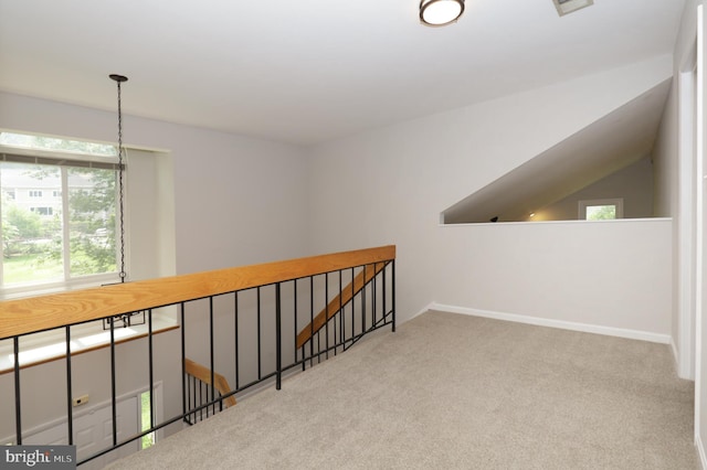 hallway with light colored carpet and vaulted ceiling