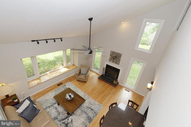 living room with a fireplace, hardwood / wood-style flooring, high vaulted ceiling, and ceiling fan