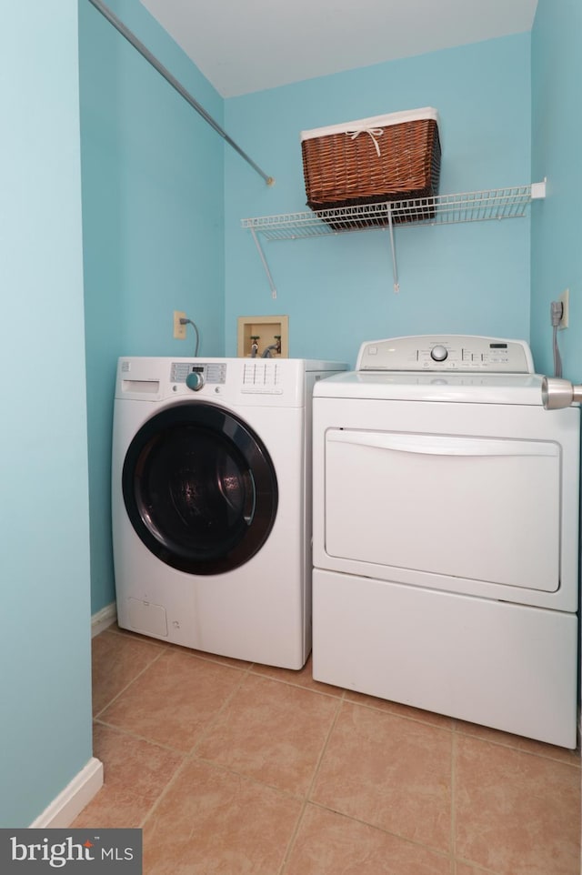 laundry area with washing machine and clothes dryer and light tile patterned floors