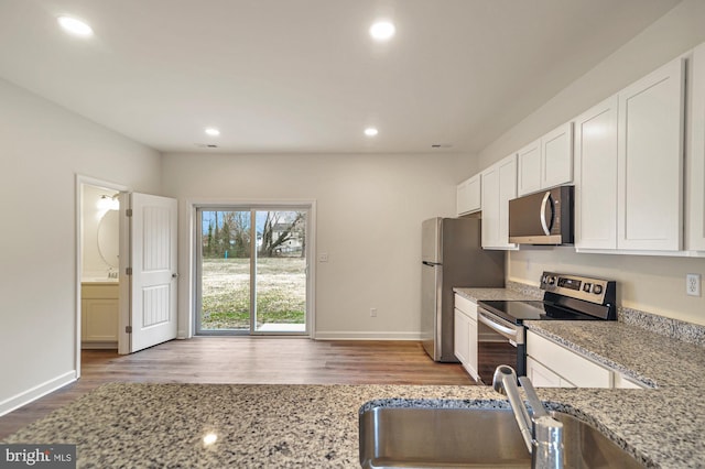 kitchen featuring white cabinets, sink, light stone countertops, and stainless steel appliances