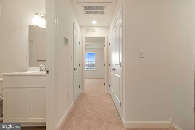 corridor with light colored carpet and sink