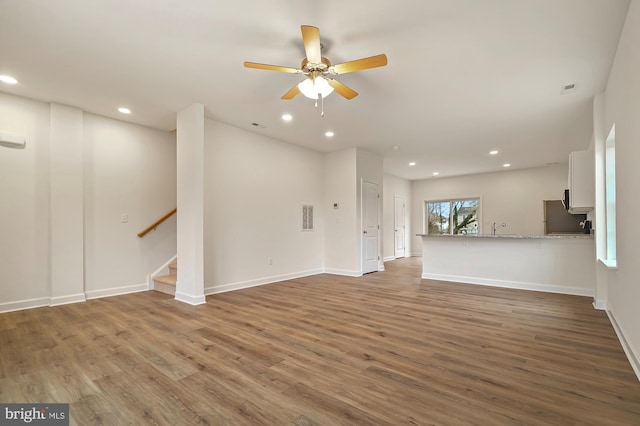 unfurnished living room featuring ceiling fan, wood-type flooring, and sink