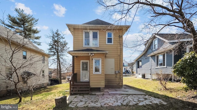 back of house featuring entry steps, a lawn, and central air condition unit