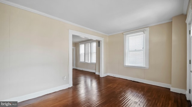 empty room featuring hardwood / wood-style flooring, baseboards, and crown molding