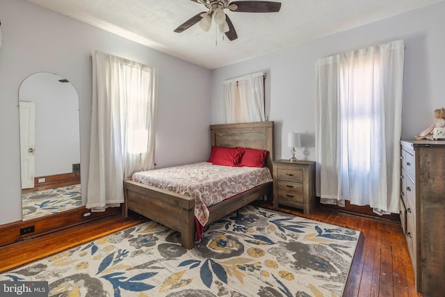 bedroom featuring a textured ceiling, ceiling fan, dark hardwood / wood-style flooring, and multiple windows