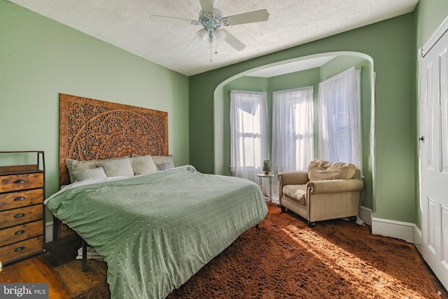 bedroom featuring ceiling fan, dark hardwood / wood-style floors, and a textured ceiling